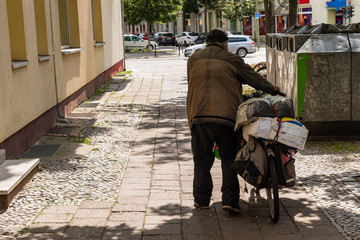 Homless Man pushing his packed Bike, Homles Man from behind, Poverty, Homelessness 