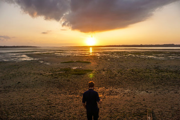 A person witnessing a sunset on a beach.