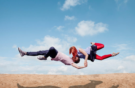Modern aerialist dancers performing, flying over beach