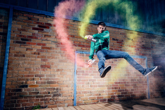 Portrait male modern dancer performing with spray paint against brick wall