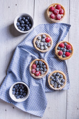 Cakes with fresh fruits on a white wooden background Top view