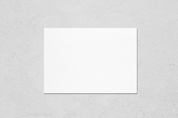 Empty white horizontal rectangle poster mockup with soft shadow on neutral light grey concrete wall...