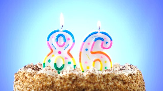 Birthday cake with a burning birthday candle. Number 86. Background changes color