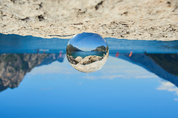 Lake Garda (Lago di Garda or Lago Benaco) seen through a glass crystal  ball placed on rock. Selective focus