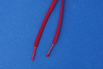 two red long shoelaces lie on a blue table
