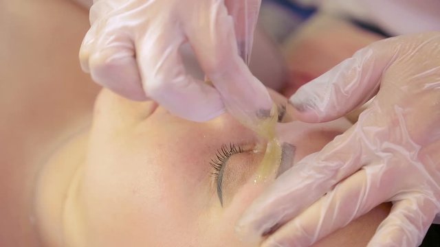 The beautician makes the correction of the eyebrows of the client sugar paste