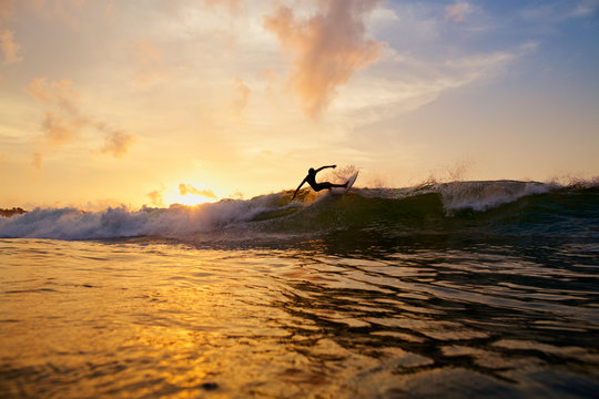 Male surfer making a turn off top of wave on sunset ocean, Sayulita, Nayarit, Mexico