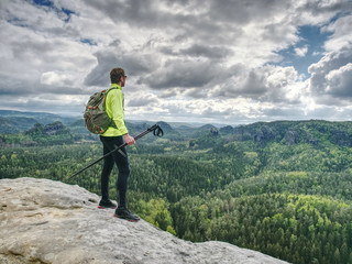 Spring rocky mountains. Hiker with backpack stand on rock