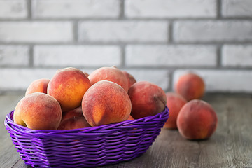 Ripe organic peaches in a purple basket on a gray background.