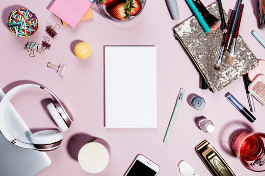 View form above blank notepad surrounded by personal belongings on pink background