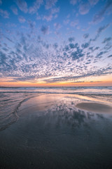 Fototapeta premium Colorful sunset at the dutch beach with beautiful reflections of the clouds in wet sand