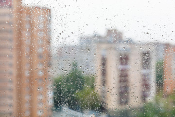 raindrops on window glass and blurred cityscape