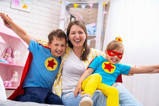 beautiful family mom and daughter with son dressed in costumes of super heroes in masks and red cloaks fun to play. The concept of a strong family children are our support and future. happy family
