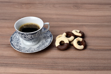 cup of coffee with cookie on table with background