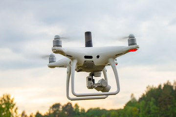 UAV White drone Quadr copter in flight with geodesic module and digital camera explores the area on...