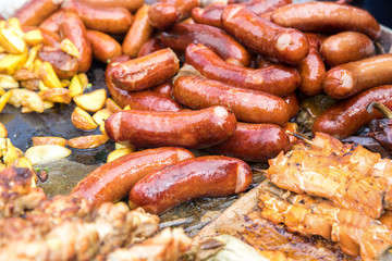 Kebabs of meat, sausages, potatoes in a rustic style fried in a large pan.