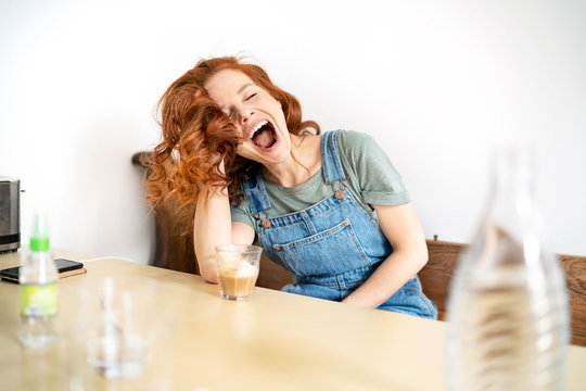 Beautiful mid adult redhead woman sitting with mouth open and eyes closed at table