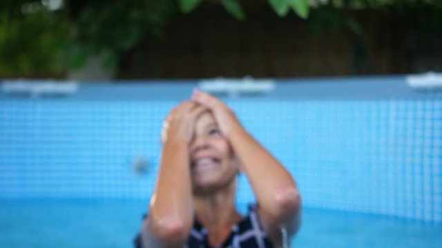 Close beautiful portrait of a teenage girl under a stream of clear water. The girl was doused with water, she laughs and falls on her back into the pool right in her clothes
