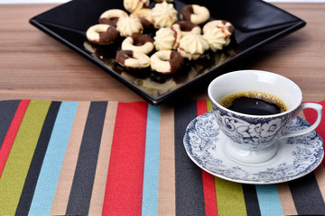 cup of coffee with cookie on table with background