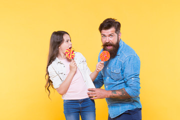 Sharing sweets with dearest people. Daughter and father eat sweet candies. Sweet dessert. Bearded hipster good daddy for adorable daughter. Sweet childhood. Girl child and dad hold colorful lollipops