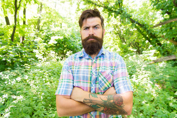 Naklejka na ściany i meble Summer style. Bearded man keeping arms crossed in casual style on natural landscape. Brutal hipster wearing fashionable mustache and beard hair style outdoor. In his personal style