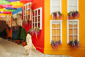 Travel tourist brunette woman in yellow dress walks the streets with bright decoration of the city.  Tilt-shift lens blur