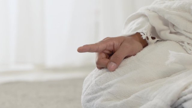 muslim man pray wearing white traditional clothes Ihram while sitting
