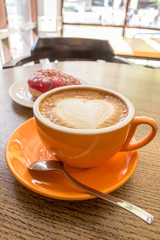 Cappuccino coffee with heart latte art and pink donut
