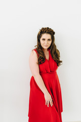 A beautiful caucasian woman in red dress posing on a white background 