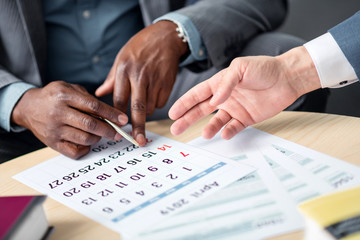 Businessman holding pen while scheduling meeting with colleague