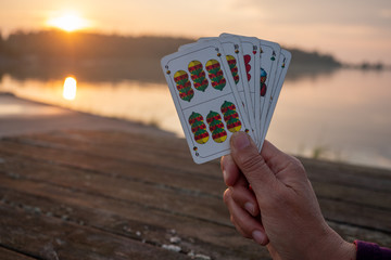 Hand holds playing cards in the sunset