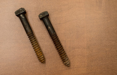 two vintage rusted large square head screws on a wood background with copy space