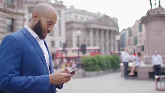 Handsome man in a suit in the city reacting to something on his phone