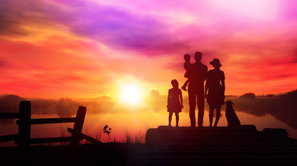Family with children watching at the setting sun in the countryside