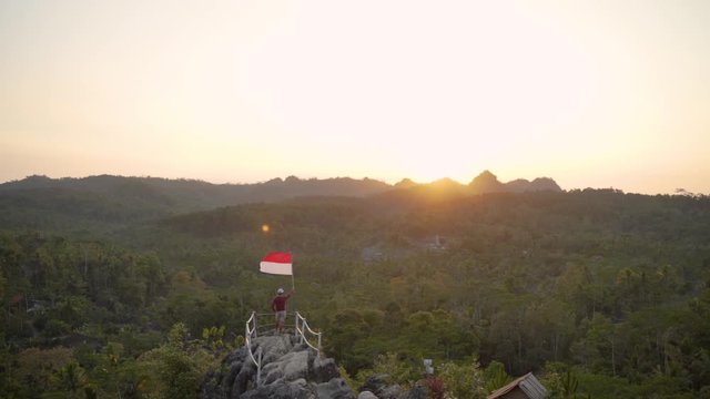 portrait of man on top of the hill in the morning rising indonesian flag celebrating independence day