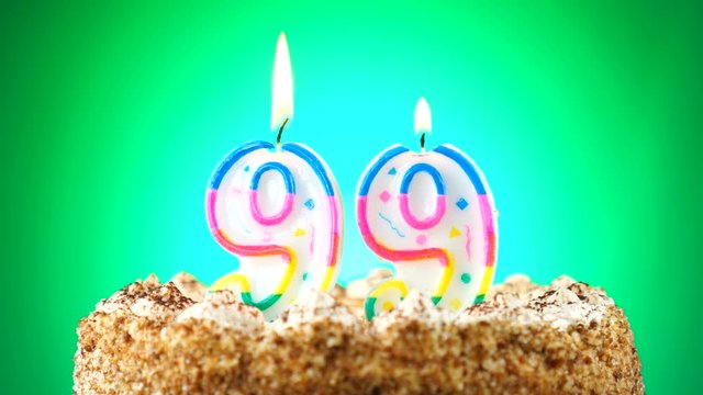 Birthday cake with a burning birthday candle. Number 99. Background changes color