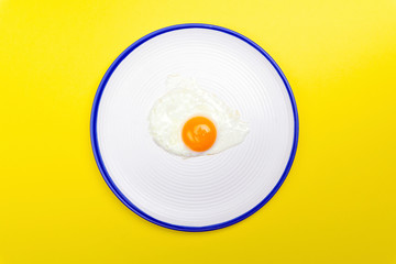 Fried eggs minimal concept on a bright yellow background. Egg yolk on a pan