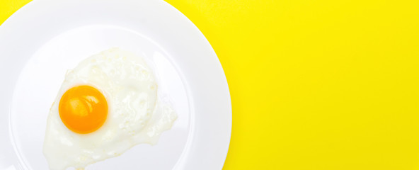 Fried eggs minimal concept on a bright yellow background. Egg yolk on a pan