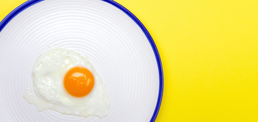 Fried eggs minimal concept on a bright yellow background. Egg yolk on a pan