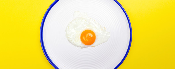 Fried eggs minimal concept on a bright yellow background. Egg yolk on a pan