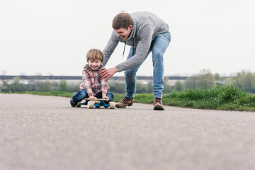 Father and son having fun, playing with skateboard outdoors
