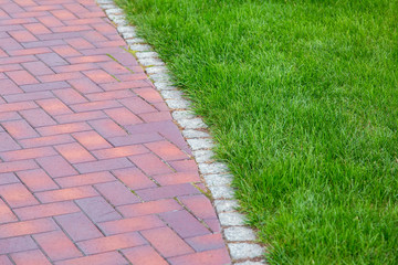 red tile walkway with stone curb and green lawn.