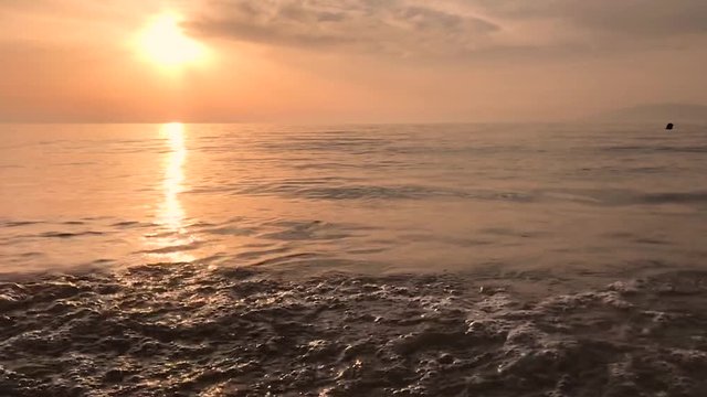 Waves gently breaking on a beach at sunset slow motion shot
