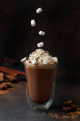 hot chocolate with cream and marshmallow in a clear glass. marshmallow falling into cacao.