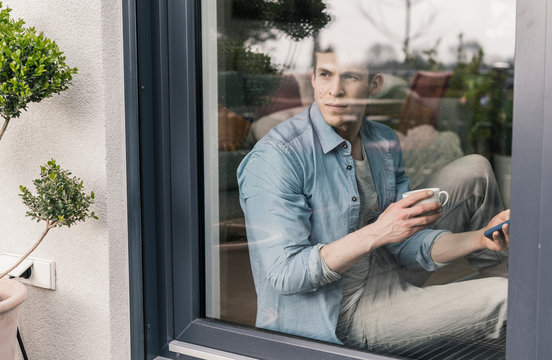Man sitting at the window, drinking coffee