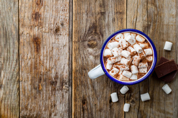 hot chocolate in an iron mug with marshmallow on old wooden background. Copy space, top view