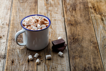 hot chocolate in an iron mug with marshmallow on old wooden background. Copy space