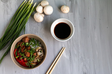 Traditional asian dish with rise and wok roasted meat, vegetables and mushrooms. Top view with space for text