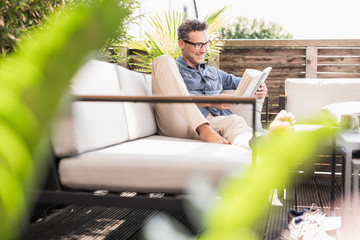 Confident man relaxing on the terrace, reading book