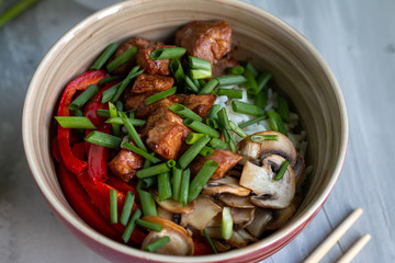 Traditional asian dish with rise and wok roasted meat, vegetables and mushrooms. Top view with space for text
